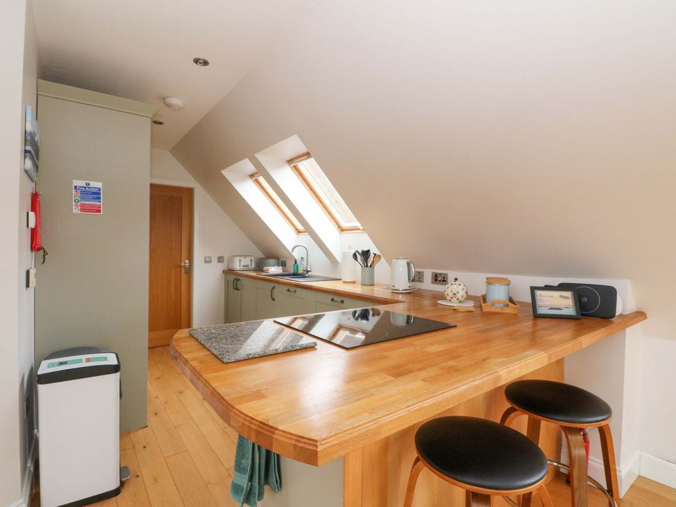 A kitchen with bar counter and stools at The Apartment in Ardgour