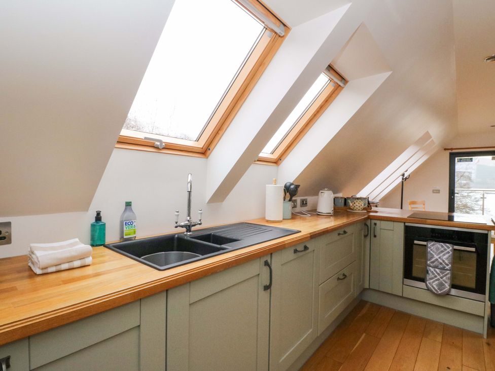 A kitchen with a sink, cabinets, and appliances at The Apartment in Ardgour