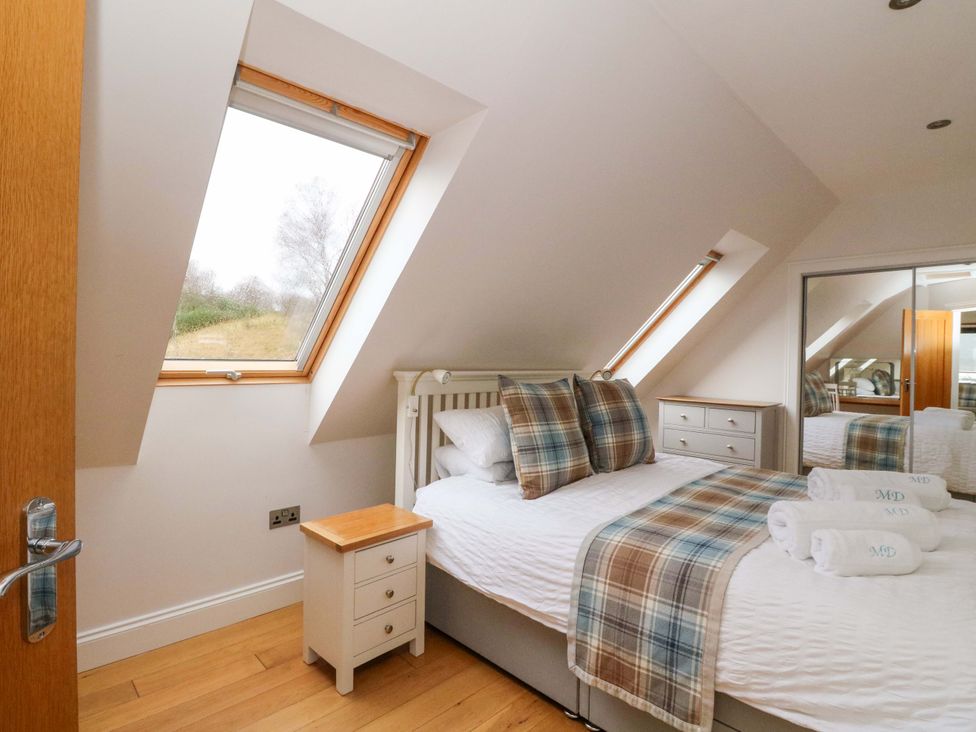 A bedroom with a bed, bedside table, and a window at The Apartment in Ardgour
