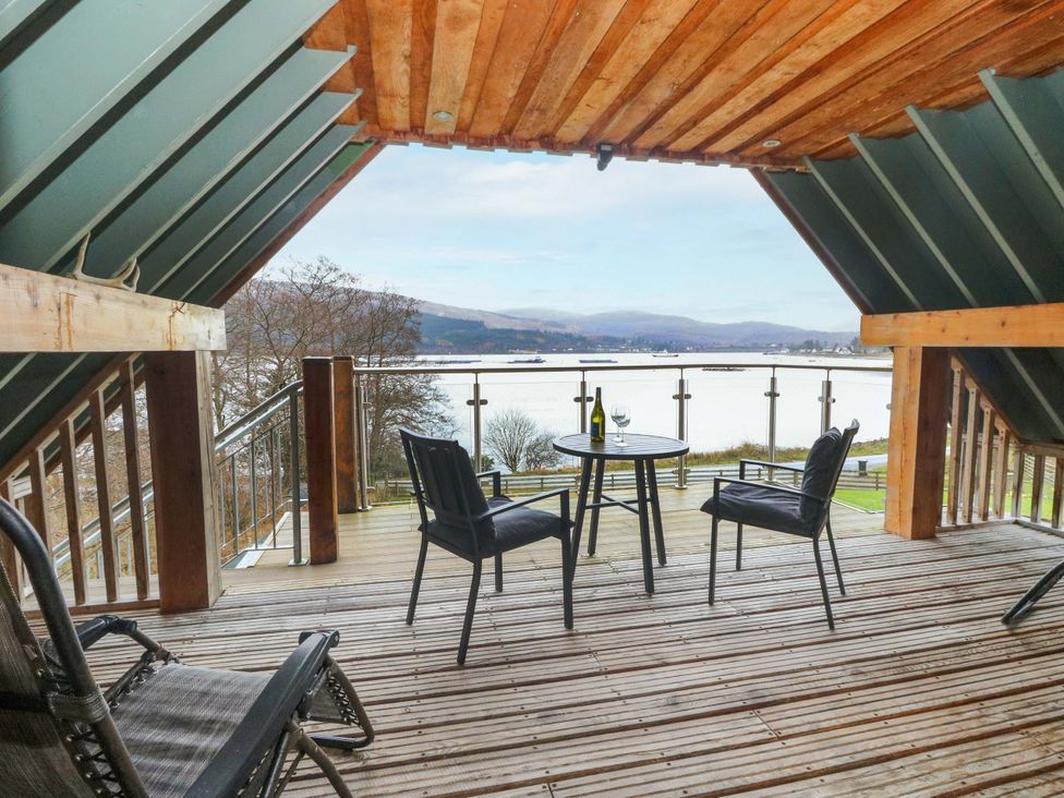 A balcony with a table and chairs overlooking a lake at The Apartment in Ardgour