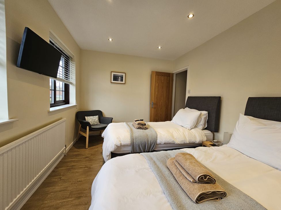 A bedroom with two beds and a chair at Seashells Cottage in Lytham St. Annes