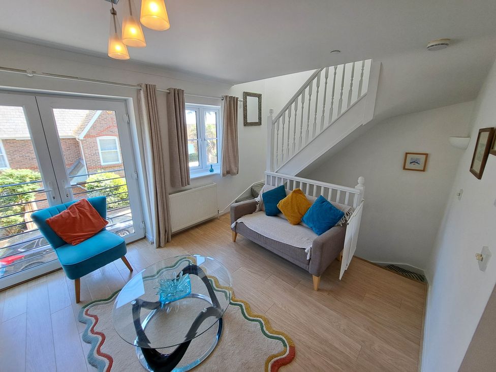 A living room with a sofa and armchair near a staircase at Castle Cove View in Castle Cove