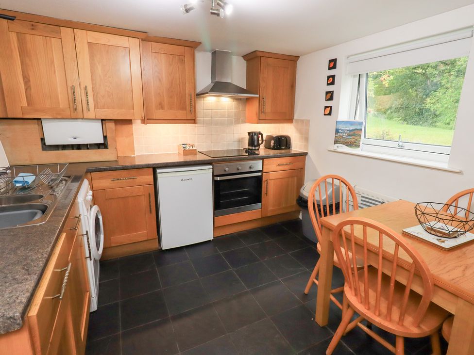 A kitchen with wooden cabinets and appliances at Kiln How Threlkeld