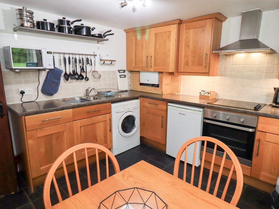 A kitchen with appliances and dining table at Kiln How in Threlkeld