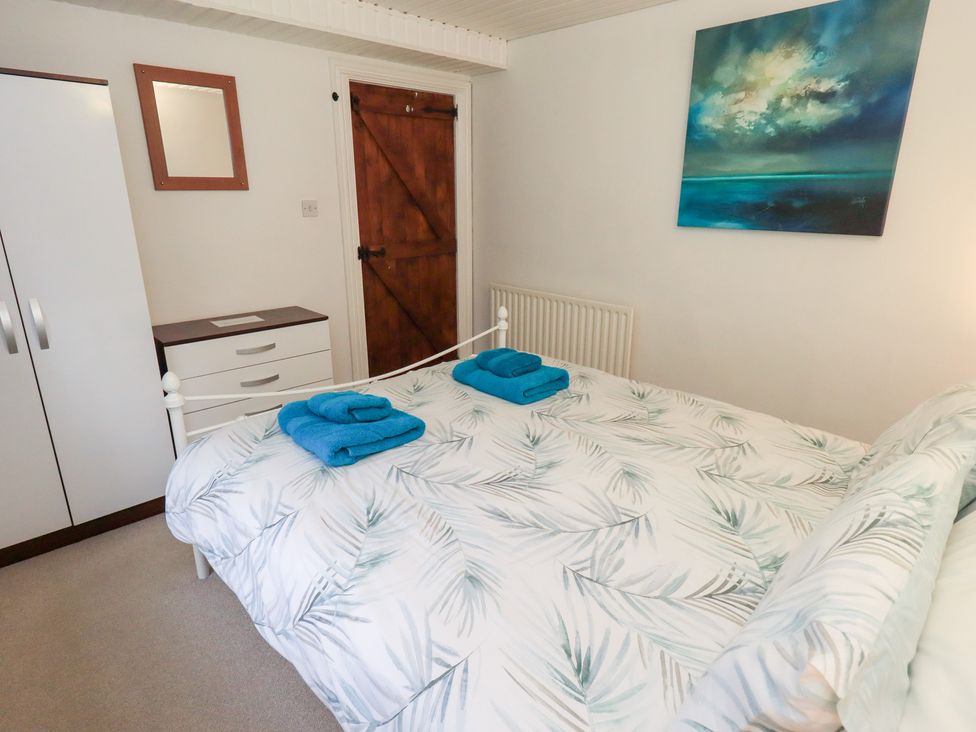 A bedroom with a bed, wardrobe and mirror at Kiln How Threlkeld
