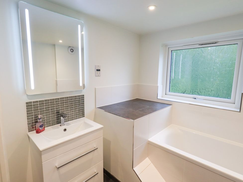 A bathroom with a bath and sink at Kiln How in Threlkeld