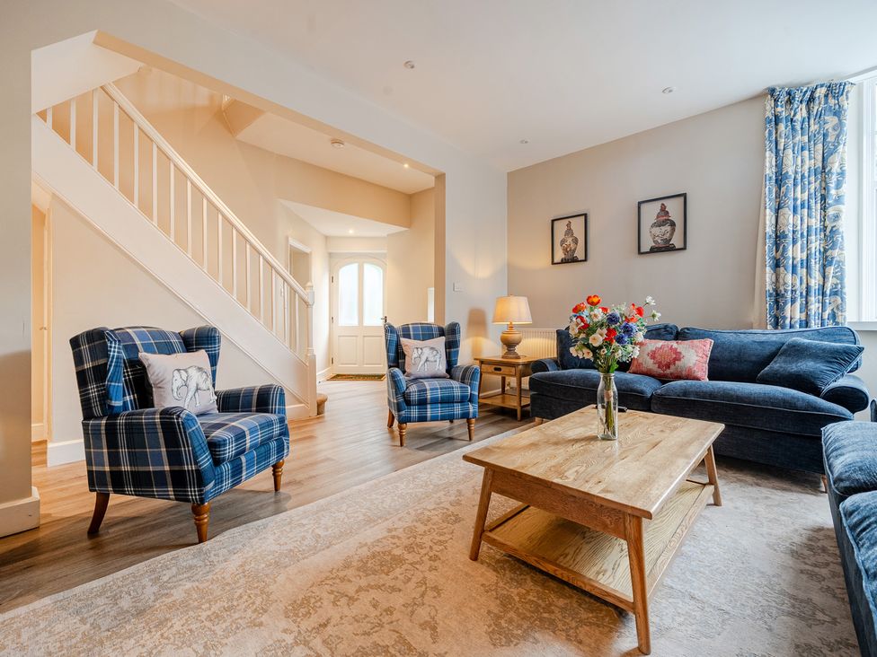 A living room with blue furniture and a staircase at Home Farmhouse at the Graythwaite Estate near Hawkshead