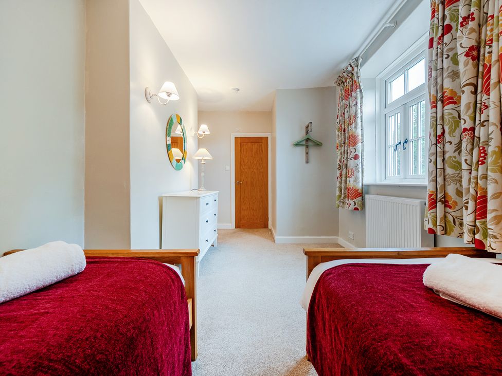 A bedroom with two beds and a wardrobe at Home Farmhouse at the Graythwaite Estate near Hawkshead