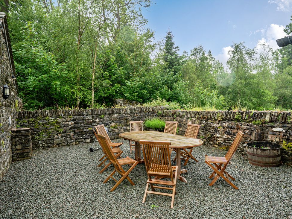 An outdoor area with a wooden table and chairs at Home Farmhouse at the Graythwaite Estate near Hawkshead