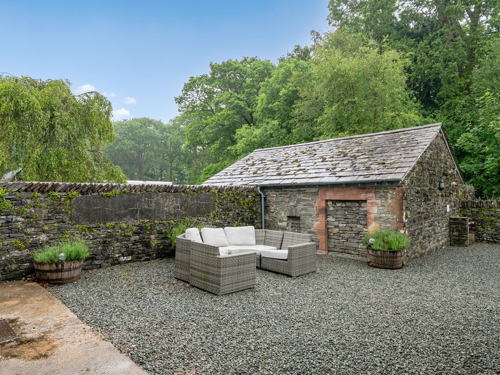 An outdoor seating area with furniture and a stone building at Home Farmhouse at the Graythwaite Estate near Hawkshead