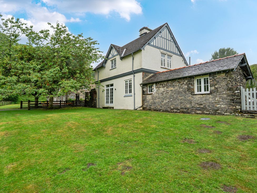 A house with a stone wall and grass outdoors at Home Farmhouse at the Graythwaite Estate near Hawkshead