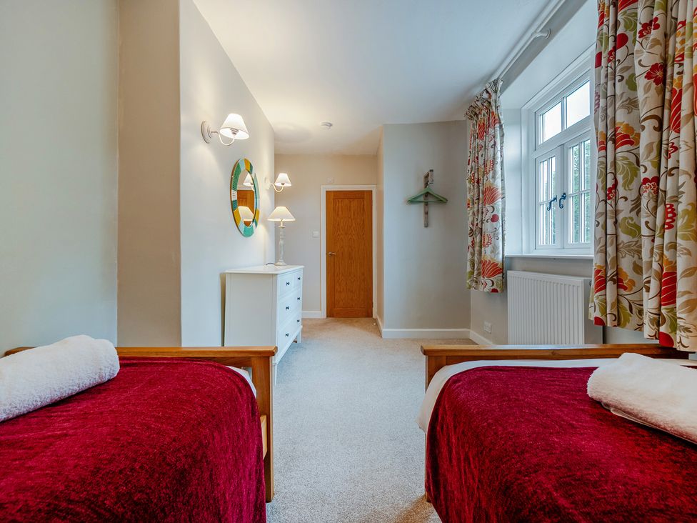 A bedroom with two beds and a dresser at Home Farmhouse at the Graythwaite Estate near Hawkshead