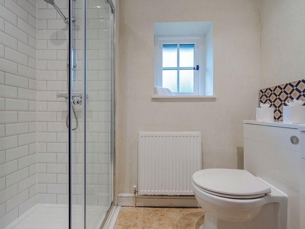 A bathroom featuring a shower, toilet, and window at Home Farmhouse at the Graythwaite Estate near Hawkshead