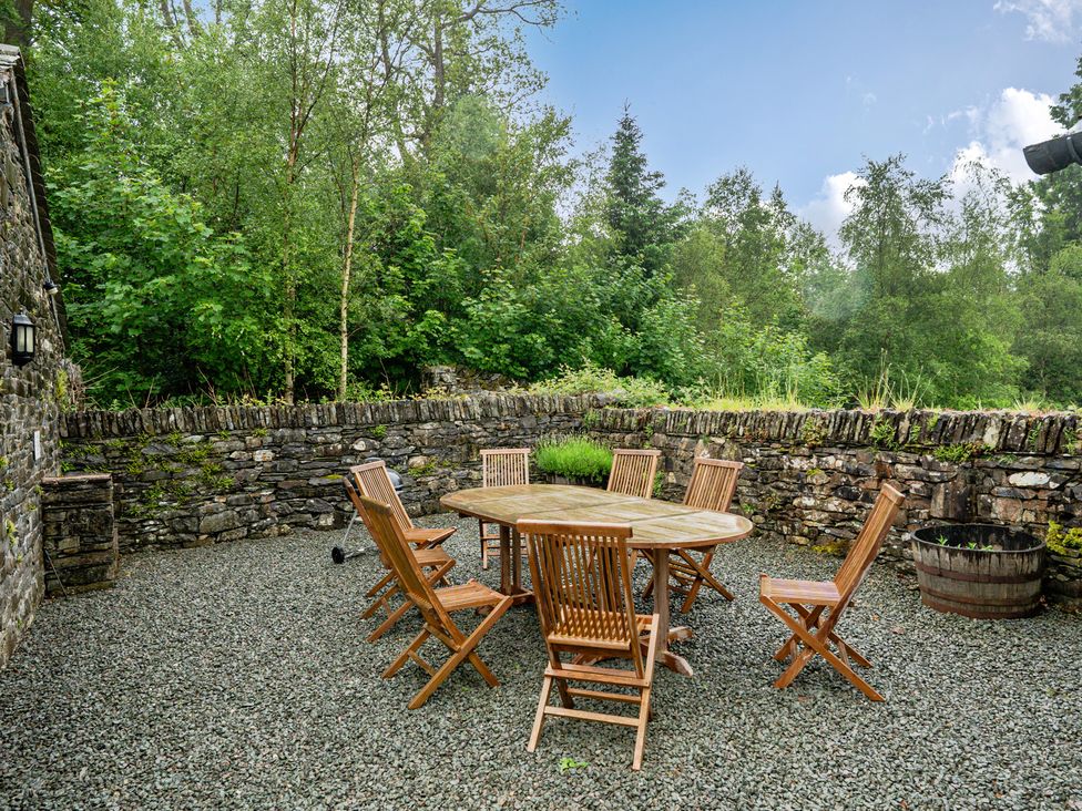 An outdoor dining area with a table and wooden chairs at Home Farmhouse at the Graythwaite Estate near Hawkshead