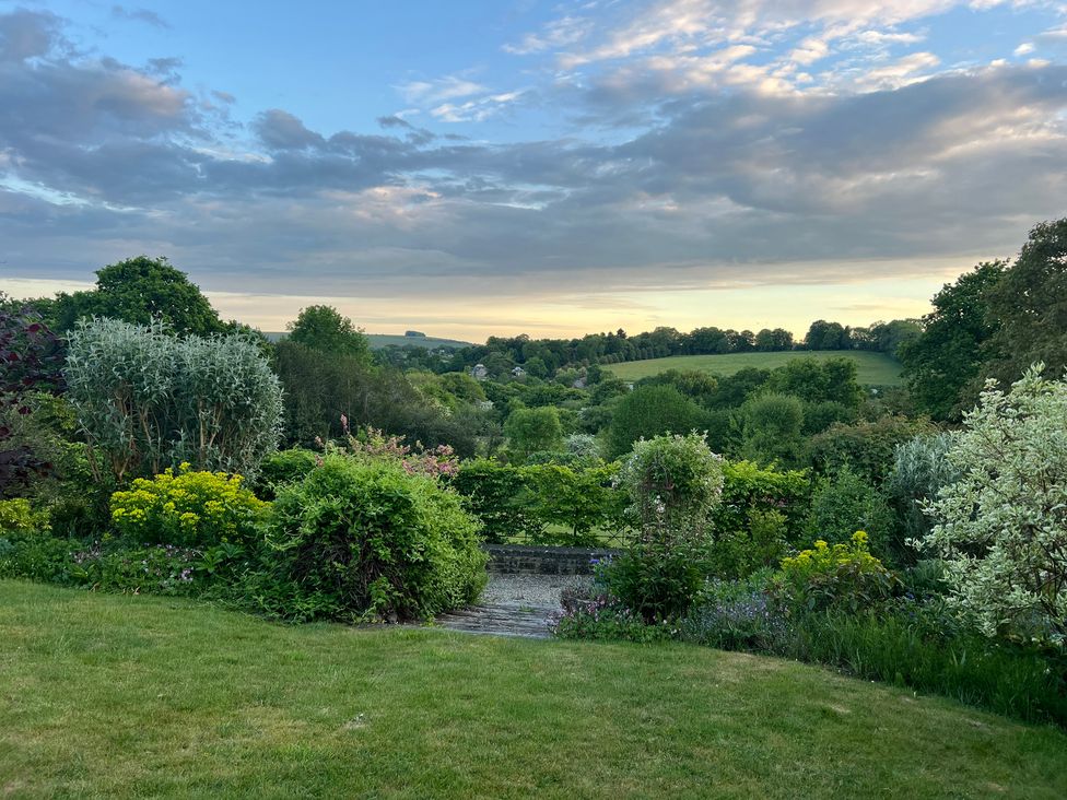 A garden with various plants and a view of hills at Samstone Donhead St. Mary near Ludwell