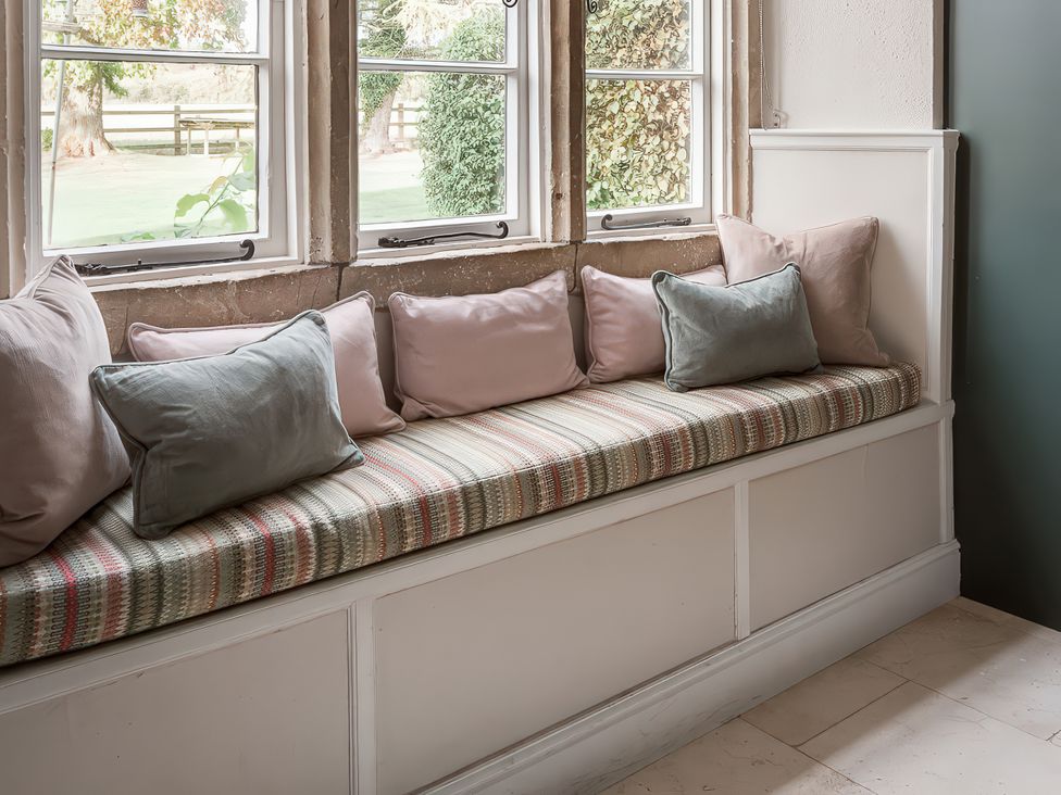 A seating area with cushions by windows at Reybridge House in Lacock