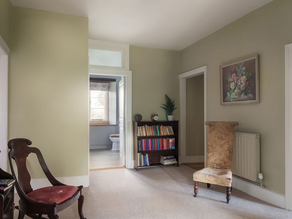 A hallway with a chair and a bookshelf at Reybridge House in Lacock