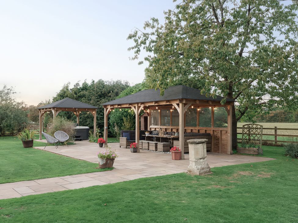 A garden with a gazebo, outdoor furniture, and planters at Reybridge House in Lacock