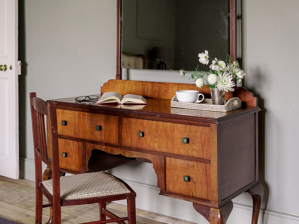 A vanity table with a mirror and chair at Reybridge House in Lacock