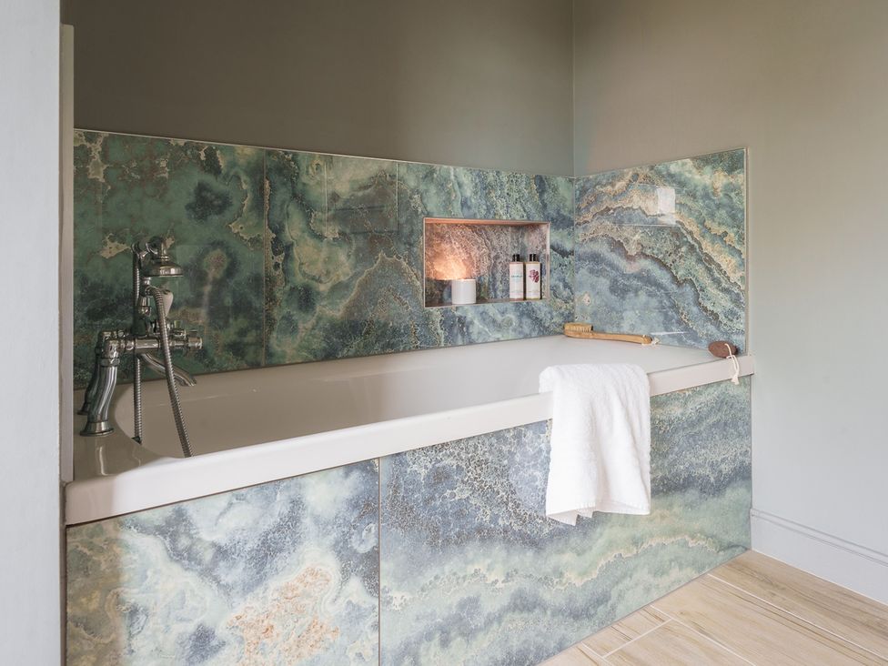 A bathroom with a bathtub and bath products at Reybridge House in Lacock