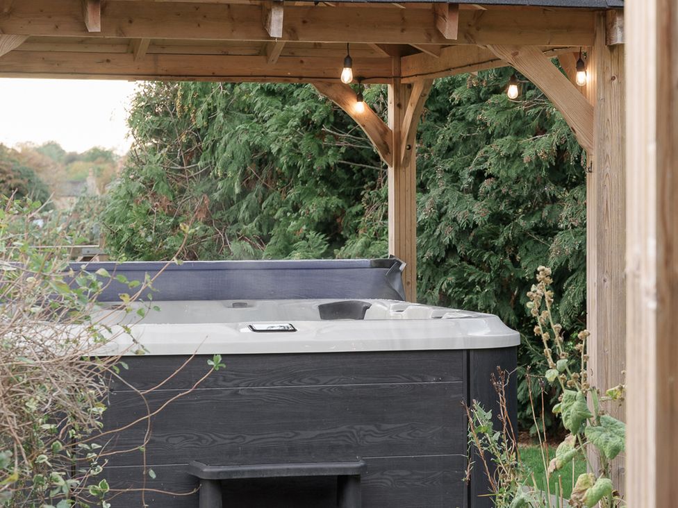 A hot tub under a wooden structure in a garden at Reybridge House in Lacock