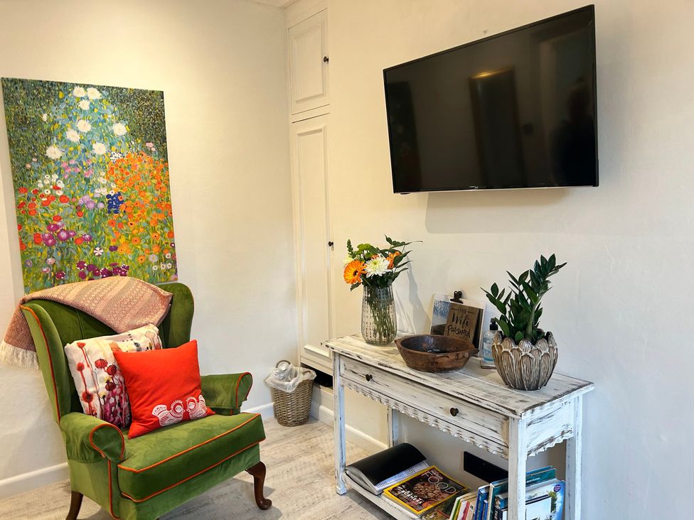 A living room with a green armchair and a television at The Escape in Malvern