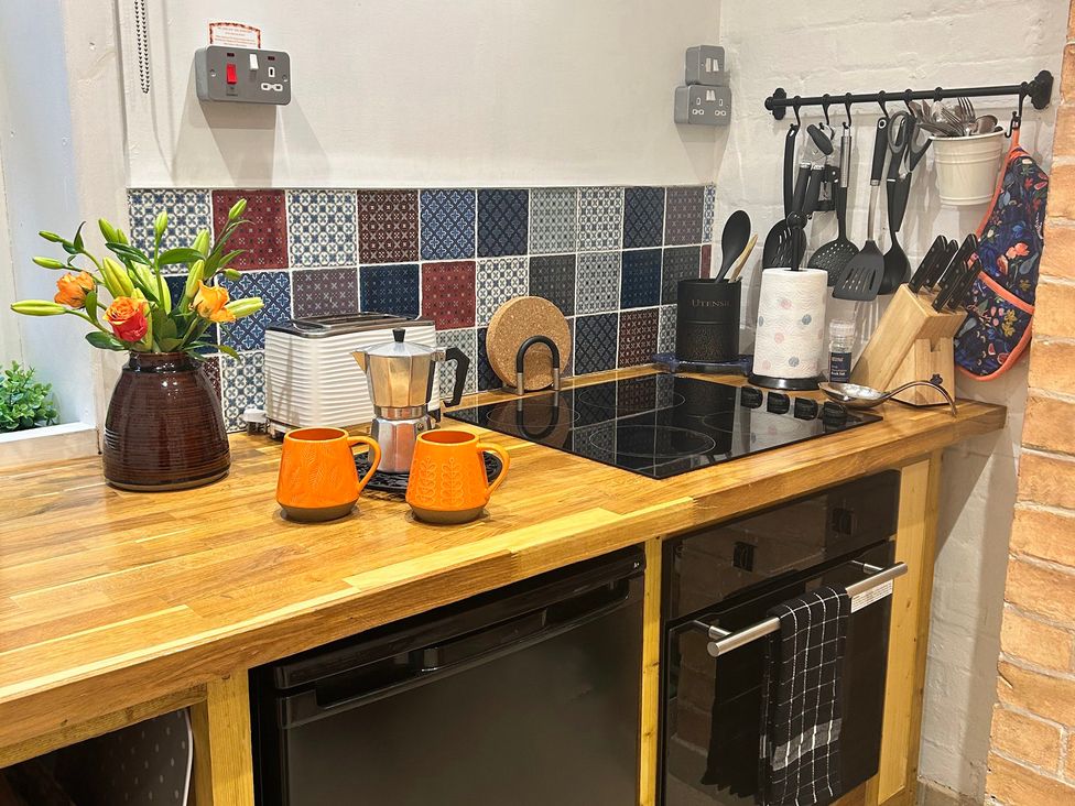 A kitchen with a counter, mugs, coffee maker, and a plant at The Escape in Malvern