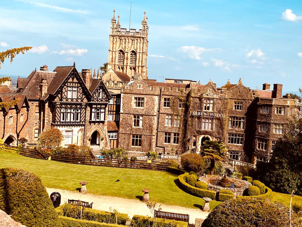 A hotel building with a garden and tower at Abbey Hotel in Malvern