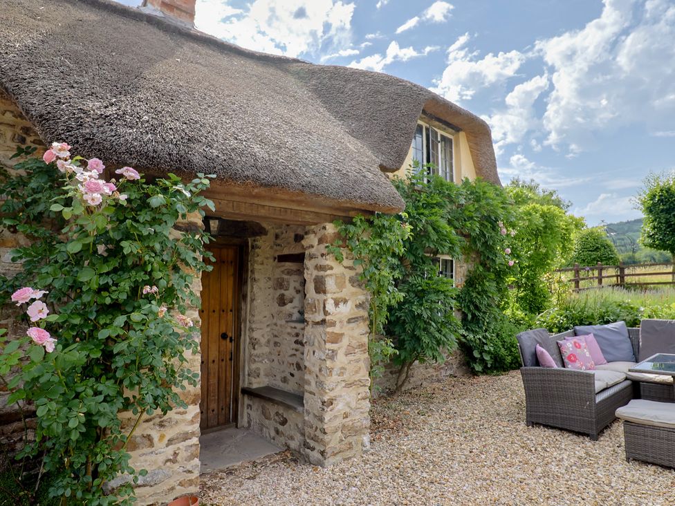 A cottage with a thatched roof and stone walls at Garden View in Wellington