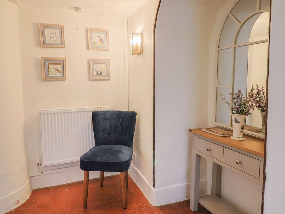 A hallway with a chair, table, and photographs at Garden View in Wellington