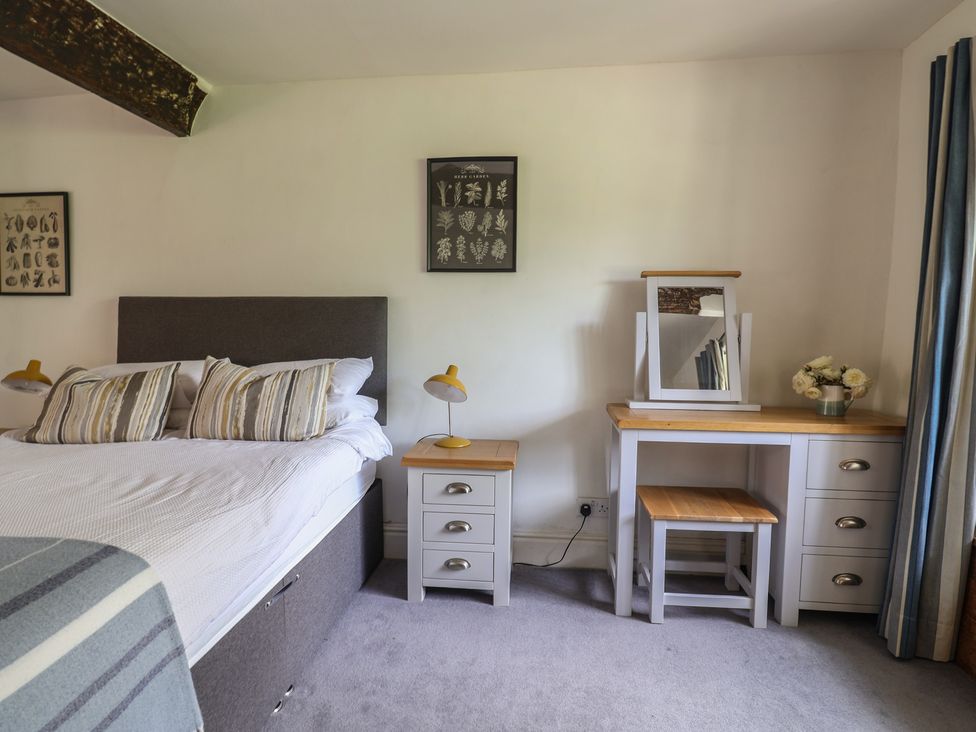 A bedroom with a bed, side table, dressing table and a mirror at Garden View, Wellington