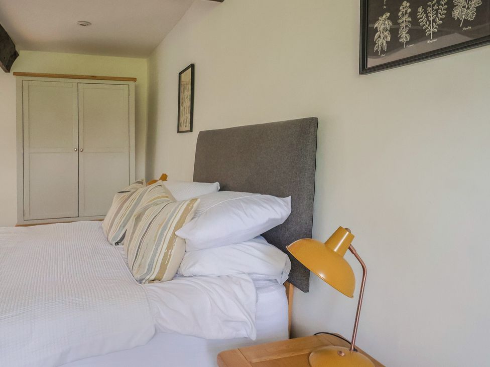 A bedroom with a bed, pillows, wardrobe, and lamp at Garden View in Wellington