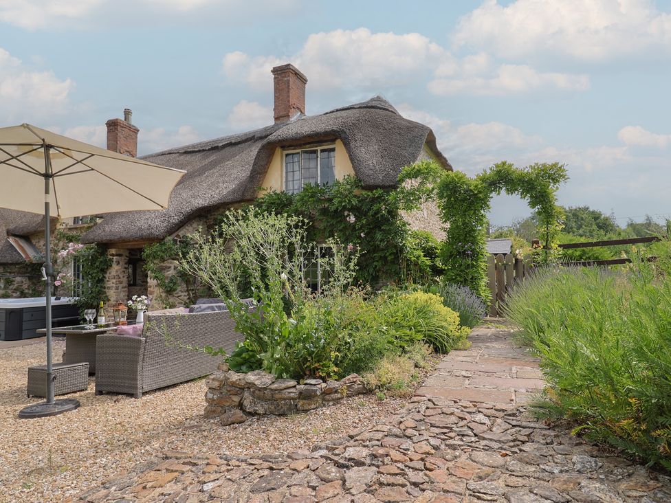 An outdoor area with a thatched roof house and garden furniture at Garden View in Wellington