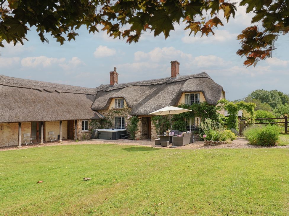 A house with a thatched roof and garden seating area at Garden View in Wellington