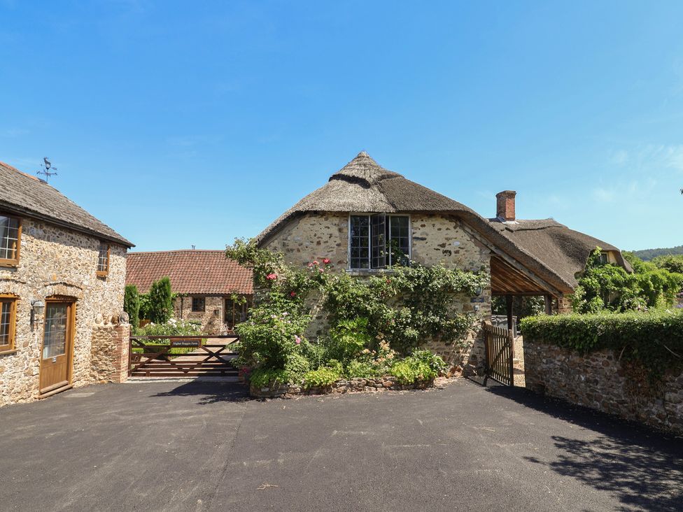 A thatched cottage with stone walls and a garden at Garden View in Wellington