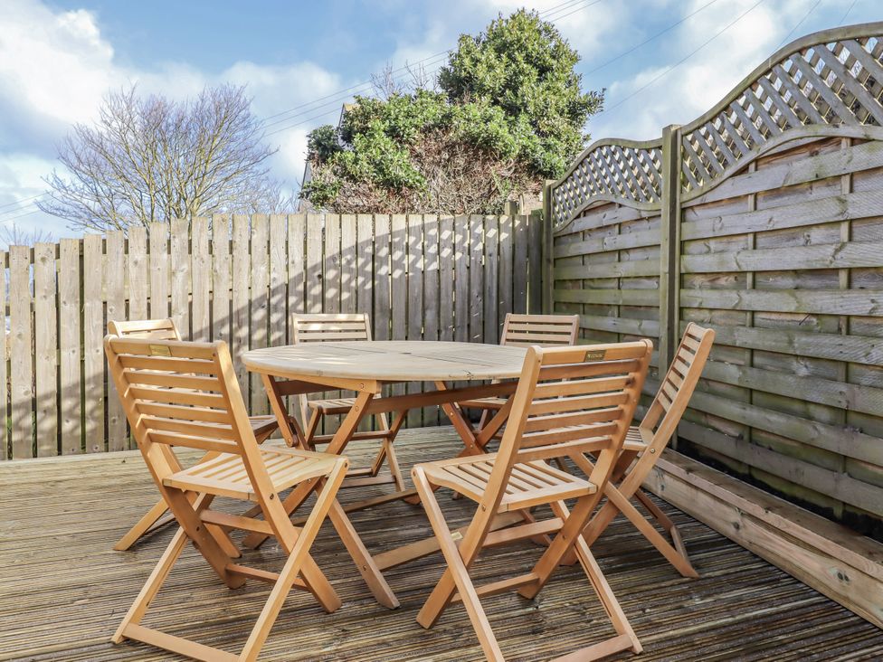An outdoor dining area with wooden furniture at Summer Rose in Craster
