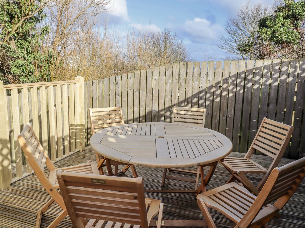 An outdoor seating area with a circular table and wooden chairs at Summer Rose in Craster
