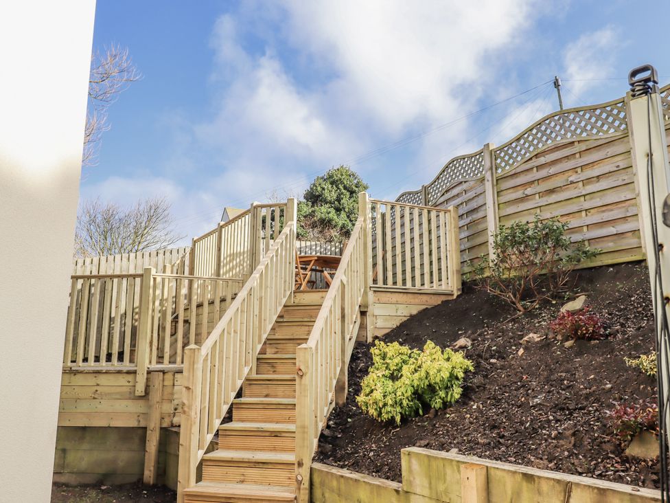 A garden with wooden stairs and a fence at Summer Rose in Craster