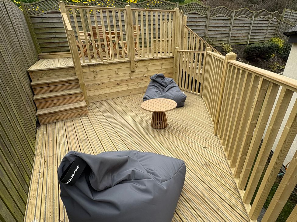A garden deck with seating and table at Summer Rose in Craster