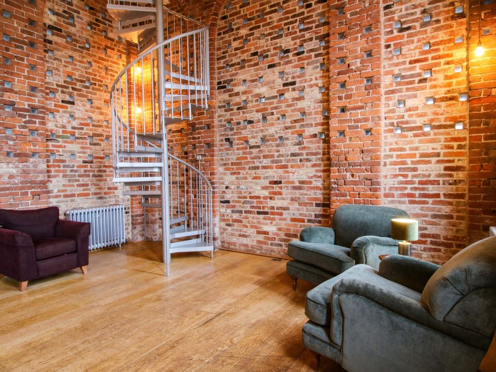 A living room with a spiral staircase and a radiator at Windy Mundy Farm in Pitchford near Shrewsbury