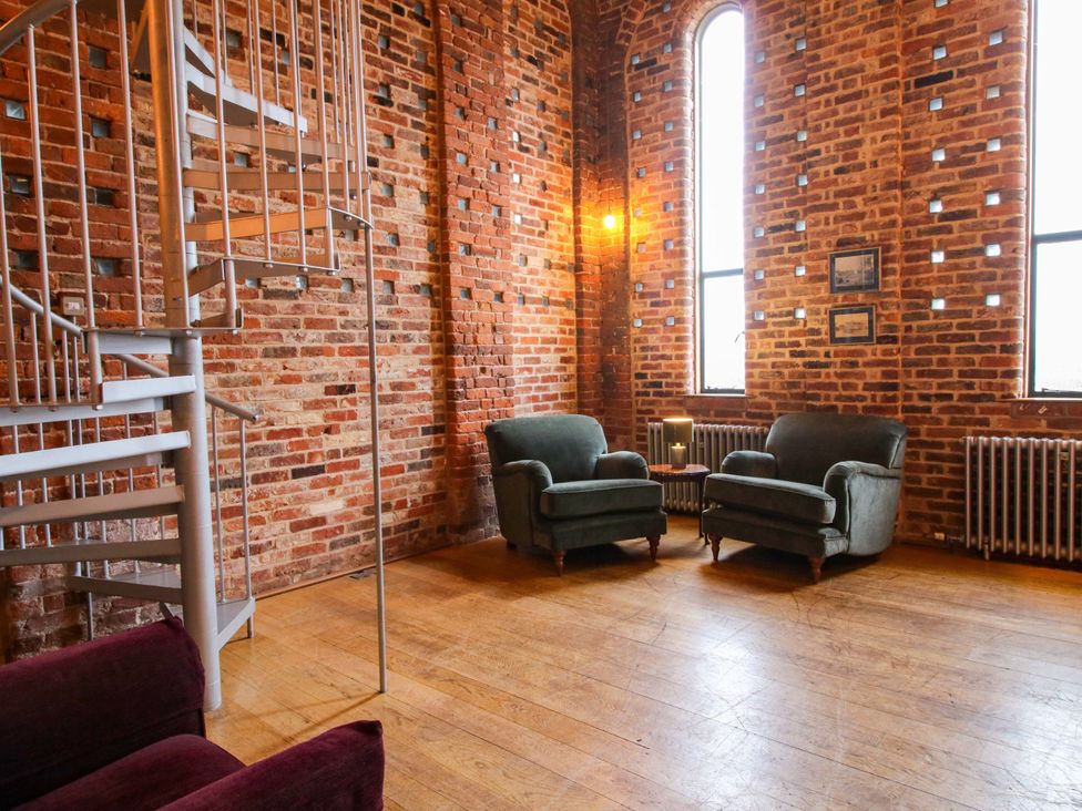 A living room with a spiral staircase and seating at Windy Mundy Farm in Pitchford near Shrewsbury