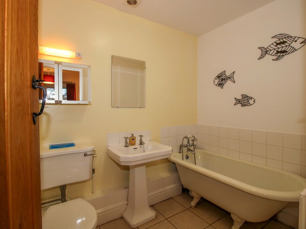 A bathroom with a bathtub, sink, and mirror at Windy Mundy Farm in Pitchford near Shrewsbury