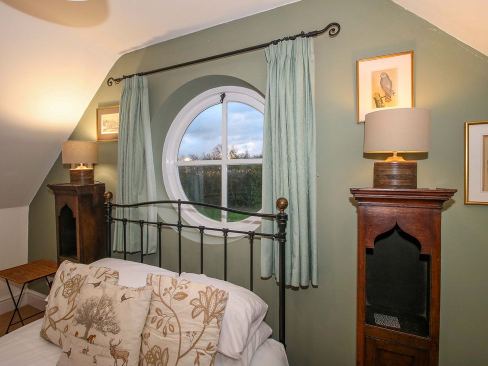 A bedroom with a round window and lamp at Windy Mundy Farm, Pitchford near Shrewsbury