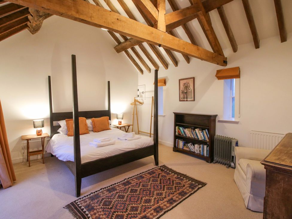 A bedroom with a four-poster bed and bookshelf at Windy Mundy Farm in Pitchford near Shrewsbury