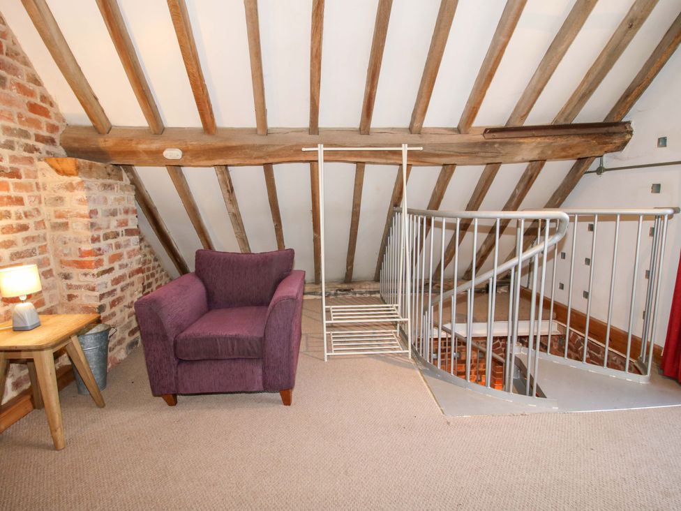 An attic with an armchair and staircase at Windy Mundy Farm Pitchford near Shrewsbury