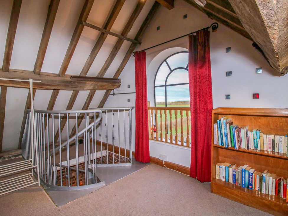 A loft with a staircase and bookshelf at Windy Mundy Farm Pitchford near Shrewsbury