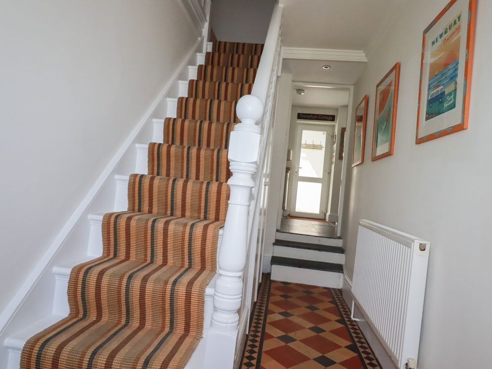 A hallway with stairs and a door at Trevethen Cottage in Crantock