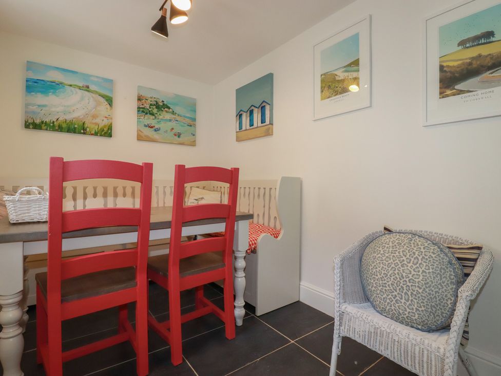 A dining room with a table and red chairs at Trevethen Cottage in Crantock