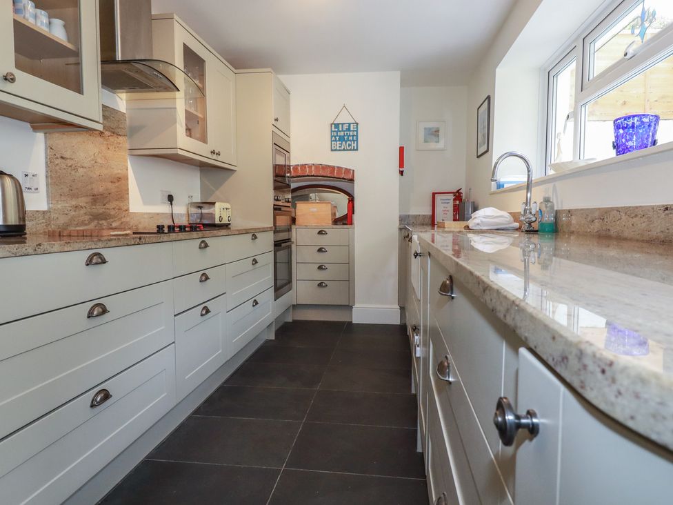 A kitchen with cabinets and appliances at Trevethen Cottage in Crantock