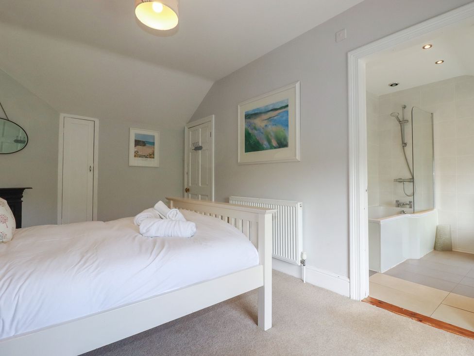 A bedroom with a bed and adjoining bathroom at Trevethen Cottage, Crantock